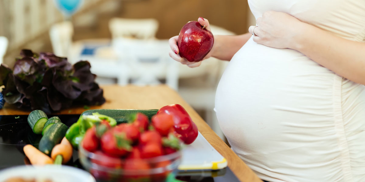 Pregnant woman holding apple