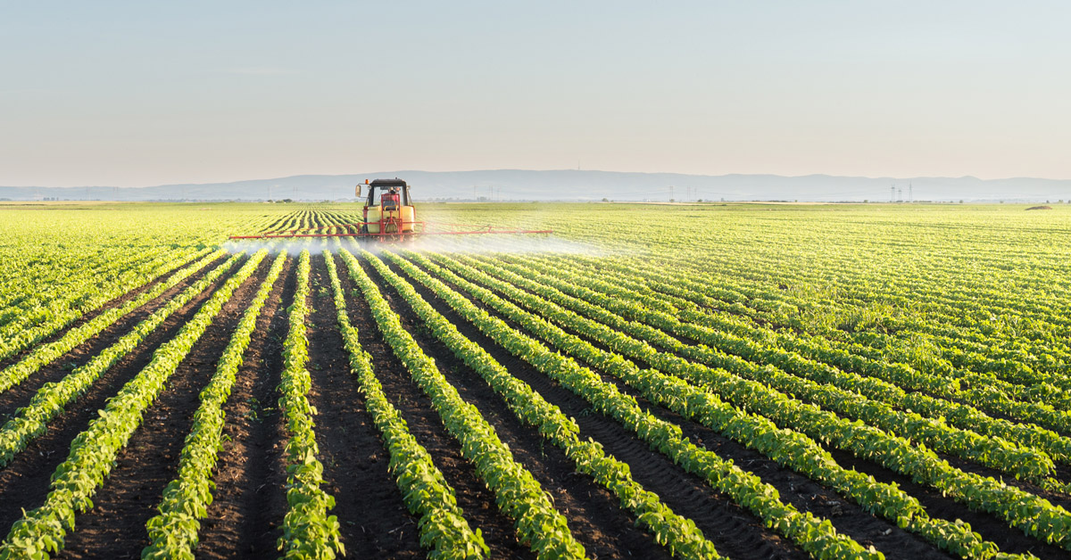 Tractor spraying soybean field with pesticides