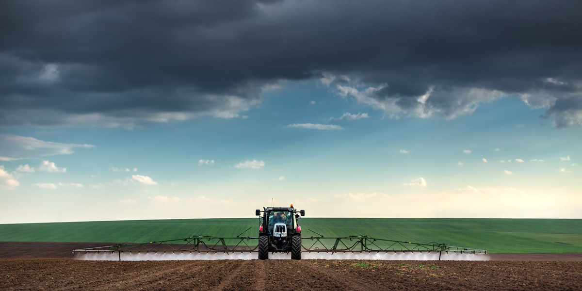 Tractor spraying Roundup Glyphosate on field