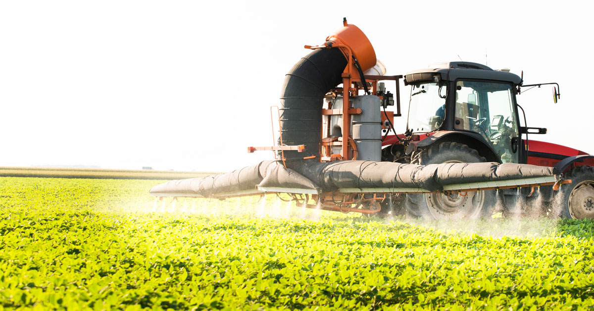 Tractor spraying soy field at sunset