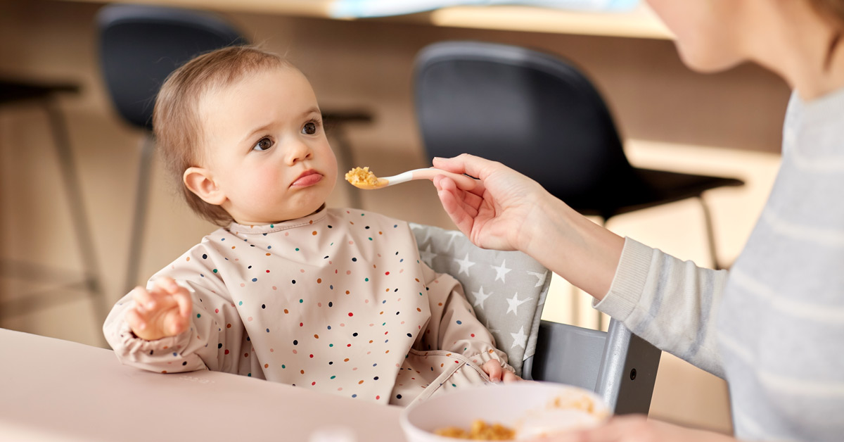 mother feeding reluctant baby